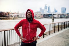 A Close-up Of Black Man Runner With Earphones And Hood On His Head In A City. Copy Space. Stock Image