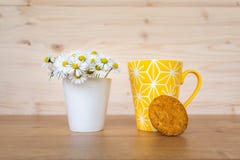 A Cookie And A Yellow Cup Of Coffee And  A Bunch Of Daisies In The Background Stock Photography