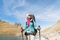 A Hiker Girl In Sunglasses And A Hat With A Backpack And Mountain Gear With Tracking Treks In Her Hands Looks At The Royalty Free Stock Photography