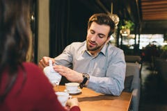 A Picture Of Guy Sitting At The Table With His Girlfriend And Pouring Some Tea Into The Cup For Them. He Is Listening To Royalty Free Stock Photography