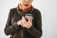 A Positive Modern Elderly Woman Is Holding A Cell Phone And Is Using It. The Older Generation And Modern Technology. Royalty Free Stock Image