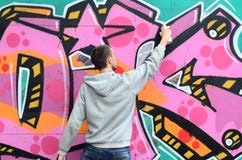 A Young Guy In A Gray Hoodie Paints Graffiti In Pink And Green C Royalty Free Stock Photo