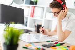 A Young Man With Glasses And Headphones Stands Near A Computer Desk. A Young Man Draws A Marker On A Magnetic Board. Royalty Free Stock Image A Young Man With Glasses And Headphones Stands Near A Computer Desk. A Young Man Draws A Marker On A Magnetic Board. Royalty Free Stock Image