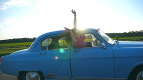 Aantrekkelijk meisje in zonnebril die uit uitstekend autoraam leunen en van reis genieten Jonge paarreis op retro auto binnen stock videobeelden Aantrekkelijk meisje in zonnebril die uit uitstekend autoraam leunen en van reis genieten Jonge paarreis op retro auto binnen stock videobeelden