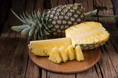 Abacaxi e fatias maduros do abacaxi em um tropi de madeira do fundo imagem de stock Abacaxi e fatias maduros do abacaxi em um tropi de madeira do fundo imagem de stock