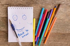 Abra o bloco de notas branco com desenho e inscrição DE VOLTA À ESCOLA com canetas com ponta de feltro coloridas e as penas de bo fotografia de stock Abra o bloco de notas branco com desenho e inscrição DE VOLTA À ESCOLA com canetas com ponta de feltro coloridas e as penas de bo fotografia de stock