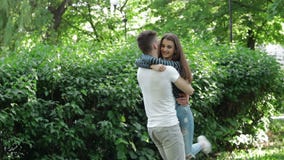 Abrazos y giros del individuo en su muchacha bonita de los brazos en el parque almacen de video Abrazos y giros del individuo en su muchacha bonita de los brazos en el parque almacen de video