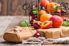 Abricots et cerises sur le fond rustique photos stock Abricots et cerises sur le fond rustique photos stock