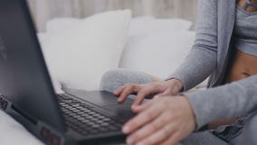 Abschluss oben Junges Mädchen in den Brillen, die auf dem Bett in einem hellen Raum und auf die Arbeit im Laptop konzentriert sit stock footage Abschluss oben Junges Mädchen in den Brillen, die auf dem Bett in einem hellen Raum und auf die Arbeit im Laptop konzentriert sit stock footage