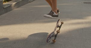 Abschluss oben von den männlichen Beinen, die Skateboard drücken und Trick auf einer Stadtstraße durchführen Langsame Bewegung stock footage Abschluss oben von den männlichen Beinen, die Skateboard drücken und Trick auf einer Stadtstraße durchführen Langsame Bewegung stock footage