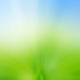 Abstract blur background of green grass field and blue sky above