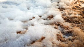 Abstrakt bild för Closeup av massor av tvålskum efter partiet för havsstranddisko som ligger på sandig kust arkivbild Abstrakt bild för Closeup av massor av tvålskum efter partiet för havsstranddisko som ligger på sandig kust arkivbild