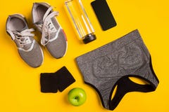 Accessori di forma fisica su un fondo giallo Scarpe da tennis, bottiglia della cima astuta e di sport dell'acqua, immagine stock Accessori di forma fisica su un fondo giallo Scarpe da tennis, bottiglia della cima astuta e di sport dell'acqua, immagine stock