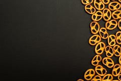 Achtergrondtextuur van gezouten smakelijke minipretzels in de traditionele vorm van de scharnierassemblage over een zwarte achter stock afbeeldingen Achtergrondtextuur van gezouten smakelijke minipretzels in de traditionele vorm van de scharnierassemblage over een zwarte achter stock afbeeldingen