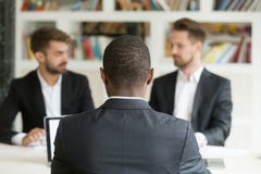 Achtermening bij Afrikaanse zakenmanzitting tegen twee Kaukasisch m royalty-vrije stock afbeeldingen Achtermening bij Afrikaanse zakenmanzitting tegen twee Kaukasisch m royalty-vrije stock afbeeldingen