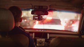 Achtermening van bestuurder in auto die zich in opstopping in avondstad bewegen stock footage Achtermening van bestuurder in auto die zich in opstopping in avondstad bewegen stock footage