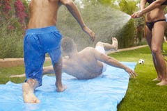Achtermening van Familie die Pret op Waterdia hebben in Tuin stock fotografie Achtermening van Familie die Pret op Waterdia hebben in Tuin stock fotografie