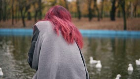 Achtermening van rode haired vrouw die in warme laag de meeuwen voeden door de vijver in park in de herfst Slowmotion schot stock footage Achtermening van rode haired vrouw die in warme laag de meeuwen voeden door de vijver in park in de herfst Slowmotion schot stock footage