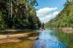 Actieve Aussie-vrouw die in rivier verre bushland springen royalty-vrije stock afbeeldingen Actieve Aussie-vrouw die in rivier verre bushland springen royalty-vrije stock afbeeldingen