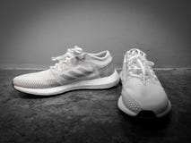 ADIDAS ÖKAR ULTRA, vita och gråa skor på en svart keramisk bakgrund arkivfoton ADIDAS ÖKAR ULTRA, vita och gråa skor på en svart keramisk bakgrund arkivfoton