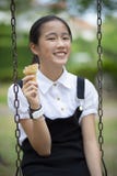 Adolescente asiático que come o cone de gelado com a cara da felicidade no verde Imagens de Stock Adolescente asiático que come o cone de gelado com a cara da felicidade no verde Imagens de Stock
