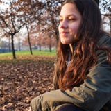 Adolescente novo de sorriso que senta-se no parque do outono fotos de stock Adolescente novo de sorriso que senta-se no parque do outono fotos de stock