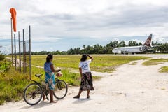 Adolescentes locais com uma bicicleta que olha um avião de partida, atol de Tarawa sul, Kiribati foto de stock Adolescentes locais com uma bicicleta que olha um avião de partida, atol de Tarawa sul, Kiribati foto de stock