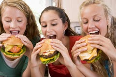 Adolescenti che mangiano gli hamburger fotografie stock Adolescenti che mangiano gli hamburger fotografie stock