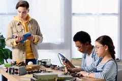 adolescents multiculturels soudant le circuit d'ordinateur avec le fer à souder et l'ami photo stock adolescents multiculturels soudant le circuit d'ordinateur avec le fer à souder et l'ami photo stock