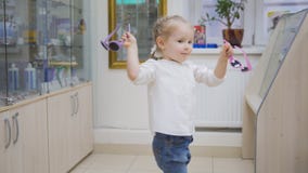 Adorable child blonde girl in ophthalmology clinic plays in hall near glasses store stock photography Adorable child blonde girl in ophthalmology clinic plays in hall near glasses store stock photography