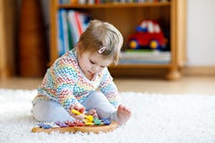 Adorable cute beautiful little baby girl playing with educational wooden music toys at home or nursery. Toddler with royalty free stock image Adorable cute beautiful little baby girl playing with educational wooden music toys at home or nursery. Toddler with royalty free stock image