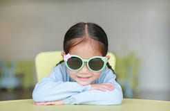 Adorable Little Asian Child Girl Laying On Children Table Wearing Sun Glasses With Smiling And Looking At Camera, Happy Kids Stock Image