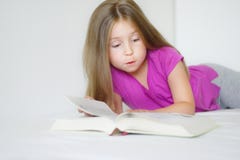 Adorable little girl lying on the bed and reading a book royalty free stock photo Adorable little girl lying on the bed and reading a book royalty free stock photo