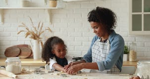 Adorable little mixed race kid cooking with mother.