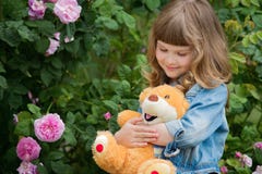 Adorable smiling girl with teddy bear in park with pink rose. royalty free stock photos Adorable smiling girl with teddy bear in park with pink rose. royalty free stock photos
