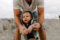 Adorably идеальная молодая семья сына малыша отца и младенца имея время потехи на песчаном пляже во время снаружи захода солнца о стоковое изображение rf Adorably идеальная молодая семья сына малыша отца и младенца имея время потехи на песчаном пляже во время снаружи захода солнца о стоковое изображение rf