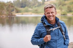 Adult man on a camping holiday standing by a lake smiling to camera, close up, Lake District, UK royalty free stock image Adult man on a camping holiday standing by a lake smiling to camera, close up, Lake District, UK royalty free stock image