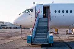 Aereo di linea con le scale di imbarco al grembiule dell'aeroporto e collegate ad un'alimentazione elettrica esterna Fotografia Stock Aereo di linea con le scale di imbarco al grembiule dell'aeroporto e collegate ad un'alimentazione elettrica esterna Fotografia Stock