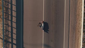 aereo Un adolescente con un pattino e le bugie sulla carreggiata ed ascolta musica sulle cuffie hippy della ragazza Vista stock footage aereo Un adolescente con un pattino e le bugie sulla carreggiata ed ascolta musica sulle cuffie hippy della ragazza Vista stock footage