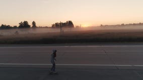 aereo un adolescente pattina su un pattino lungo una strada abbandonata fuori della città all'alba Ragazza in una maglietta felpa stock footage aereo un adolescente pattina su un pattino lungo una strada abbandonata fuori della città all'alba Ragazza in una maglietta felpa stock footage