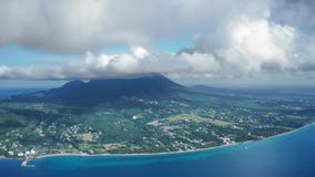 Aerial drone camera zooming Nevis Peak with the city on the coast Saint Kitts and Nevis