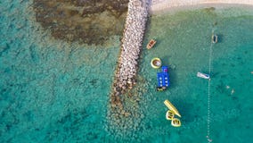 Aerial image of stone pier and wonderful, turquoise shallow sea with vessels and swimmers at the town of Rogoznica, Croatia during