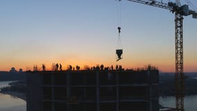 Aerial shot of construction site with cranes and workers at sunset