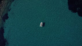 Aerial shot of happy couple relaxing and sunbathing on a boat parked in the middle of the most clean Mediterranean water stock video footage Aerial shot of happy couple relaxing and sunbathing on a boat parked in the middle of the most clean Mediterranean water stock video footage