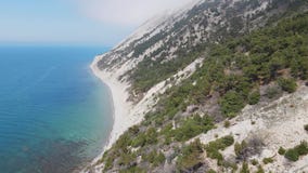 Aerial view of coastline with blue sea and highest cliff with pine trees. Summer day on Black sea