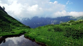 Aerial view of emerald lake high in the mountains in Abkhazia overlooking the mountains and ravines and running clouds stock footage Aerial view of emerald lake high in the mountains in Abkhazia overlooking the mountains and ravines and running clouds stock footage