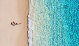 Aerial view of a girl on the beach on Bali, Indonesia. Vacation and adventure. Beach and turquoise water. Top view from drone at b