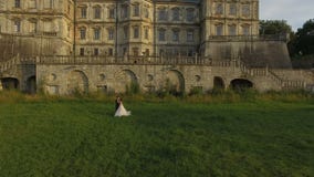 Aerial view of groom comes to bride and caresses her on castle background stock video Aerial view of groom comes to bride and caresses her on castle background stock video