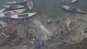 Aerial view of men cleaning dirty shore of Ganges in Varanasi.