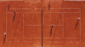 Aerial view. Players are playing tennis on orange court. stock video Aerial view. Players are playing tennis on orange court. stock video